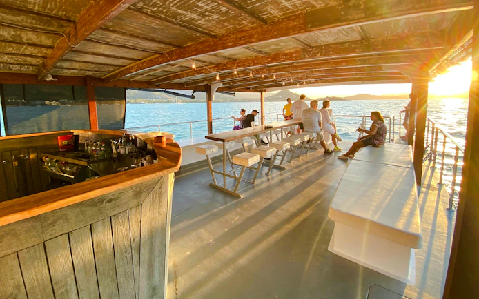 Sundowner cruise bar with people enjoying sunset views at Airlie Beach.