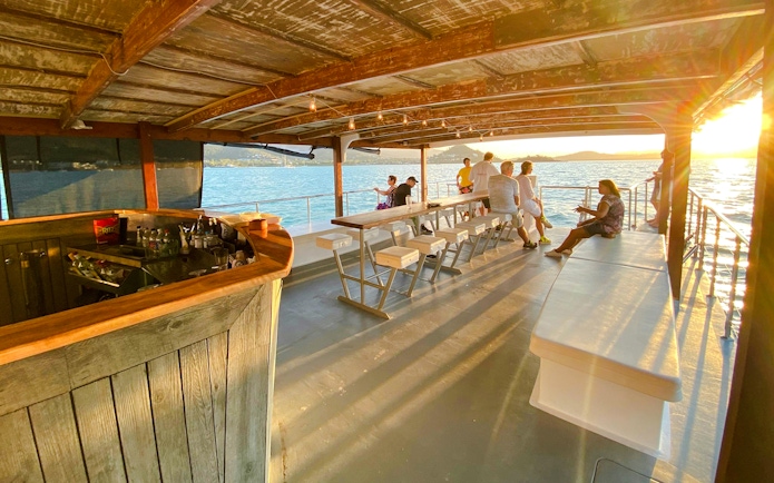 Sundowner cruise bar with people enjoying sunset views at Airlie Beach.