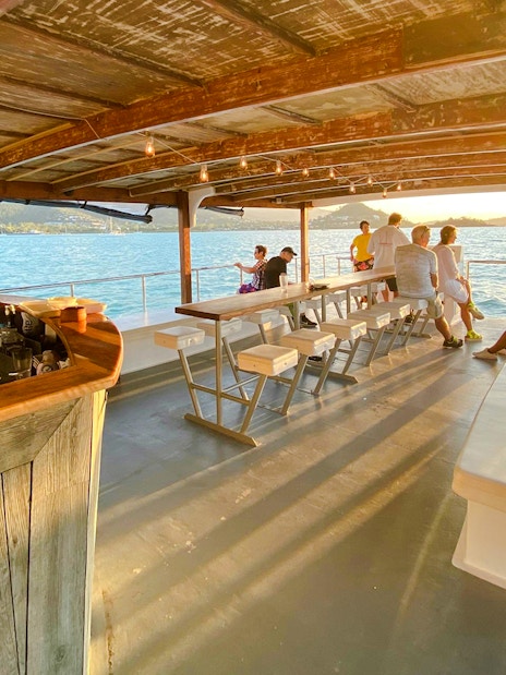 Sundowner cruise bar with people enjoying sunset views at Airlie Beach.
