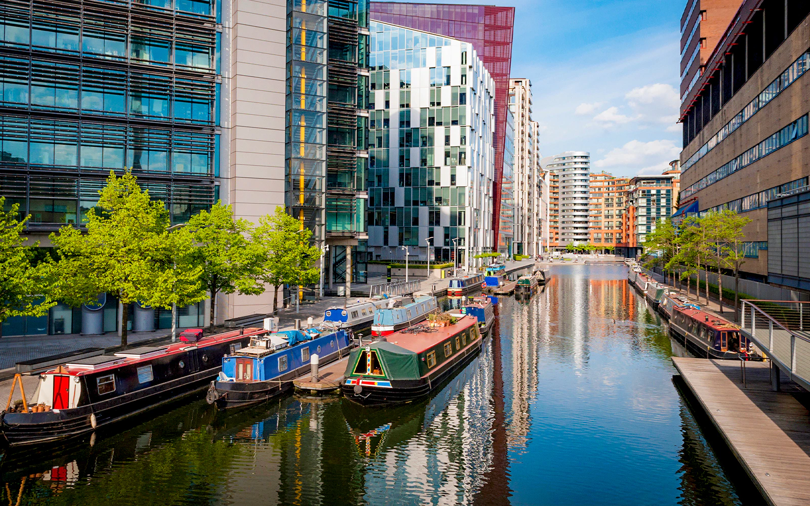 Canal boats moored along Regent's Canal in London with modern buildings in the background.