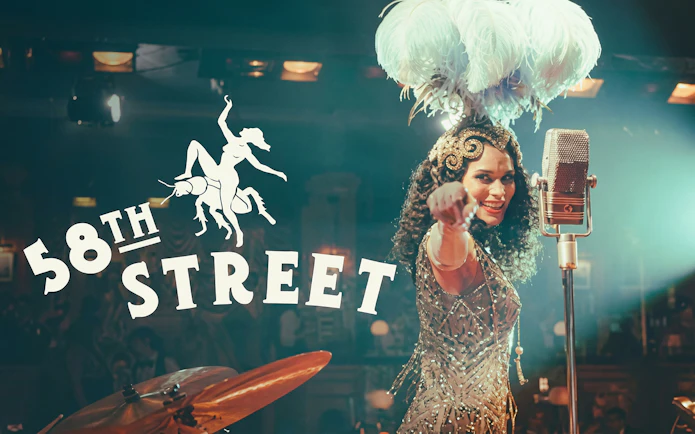 Performer in vintage attire on stage with microphone at 58th Street show.