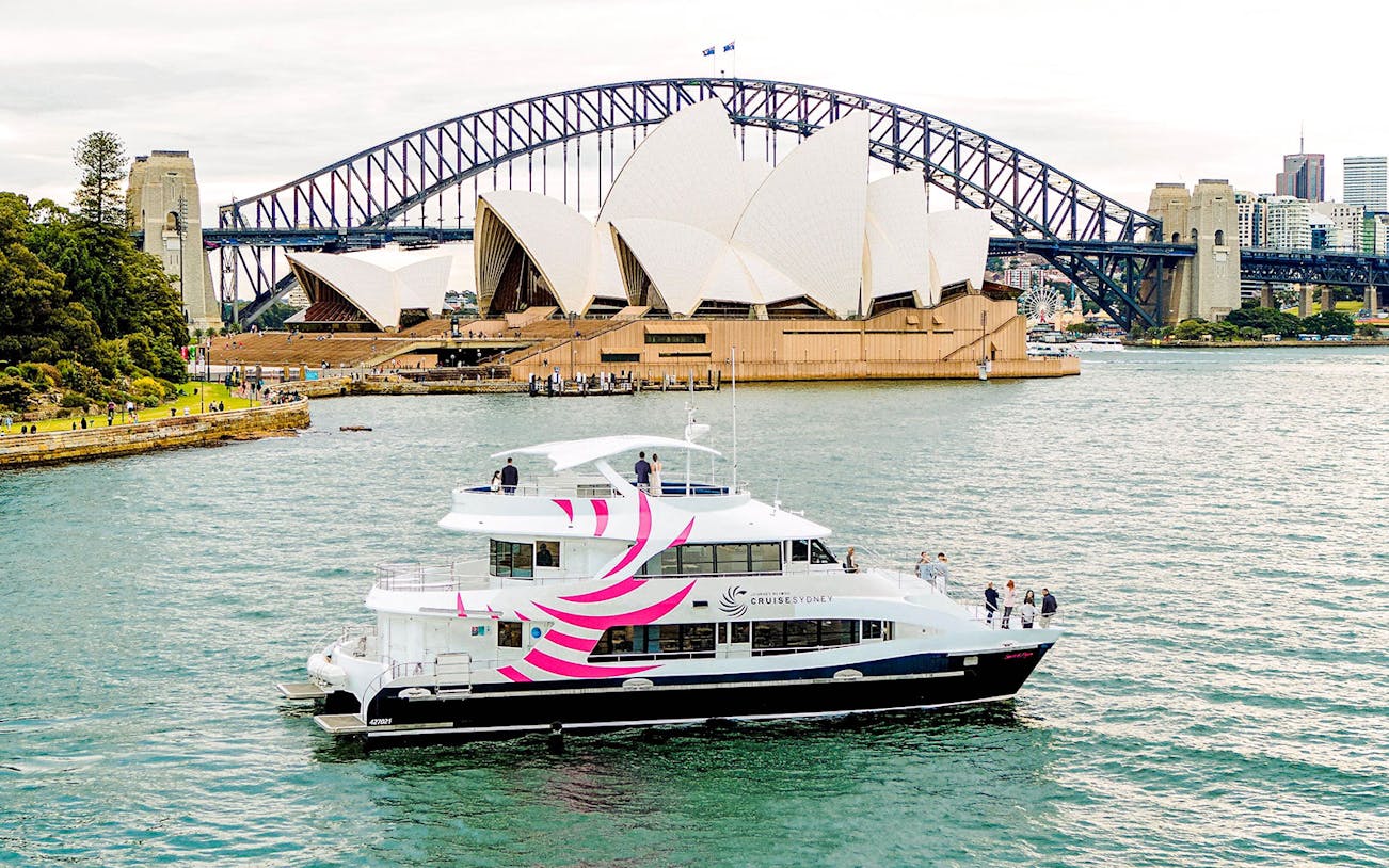 Luxury vessel cruising on Sydney Harbour with Opera House and Harbour Bridge in view.