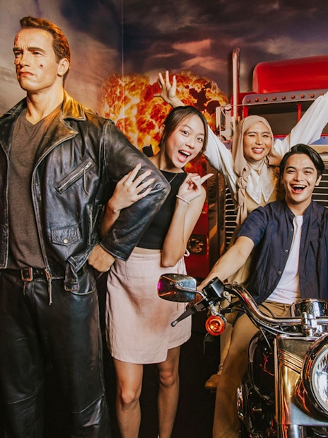 Wax figure of Terminator at Madame Tussauds Singapore with visitors posing nearby.