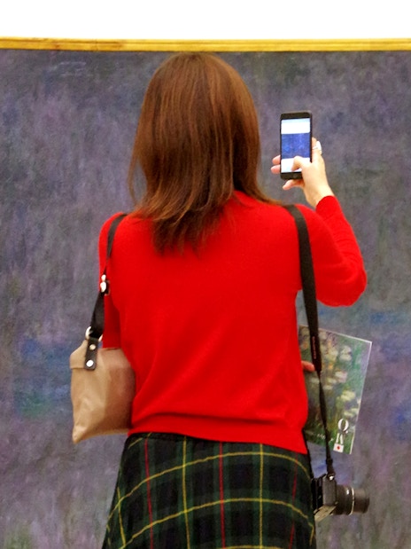 Tourist photographing Monet's Water Lilies at Orangerie Museum, Paris.