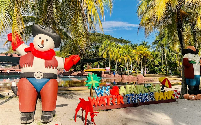 Entrance of A'Famosa Melaka Waterpark with colorful statues and palm trees.
