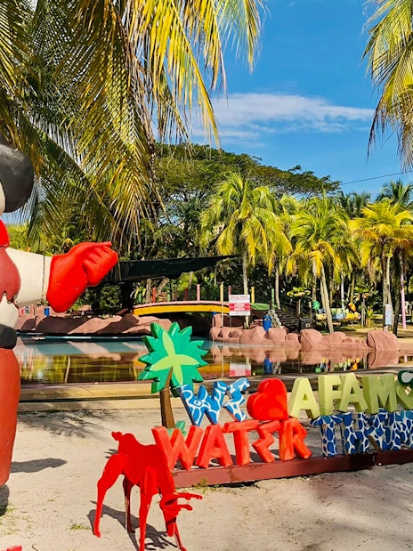 Entrance of A'Famosa Melaka Waterpark with colorful statues and palm trees.