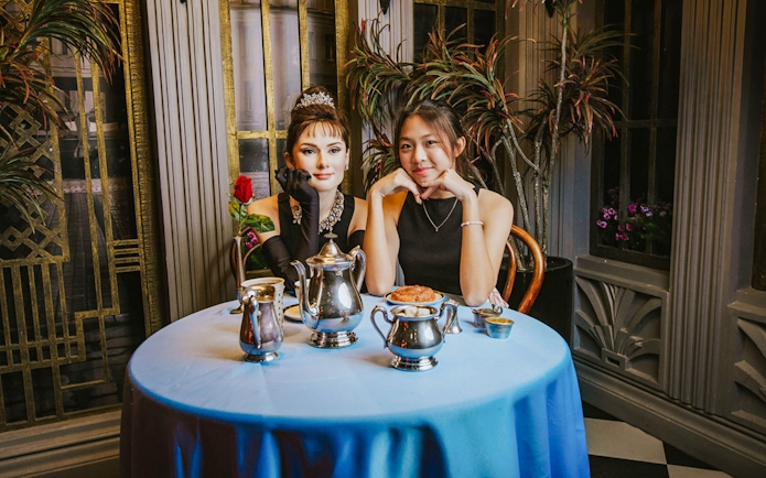Woman posing with Audrey Hepburn wax figure at Madame Tussauds Singapore.