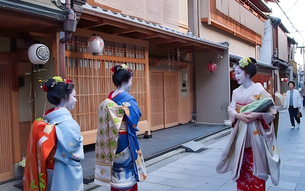 Geisha walking in traditional attire on a street in Kyoto, Japan.
