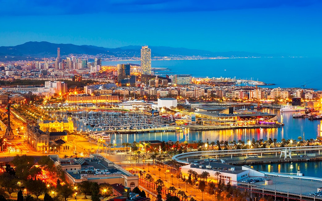Monaco skyline at night with illuminated harbor and cityscape.