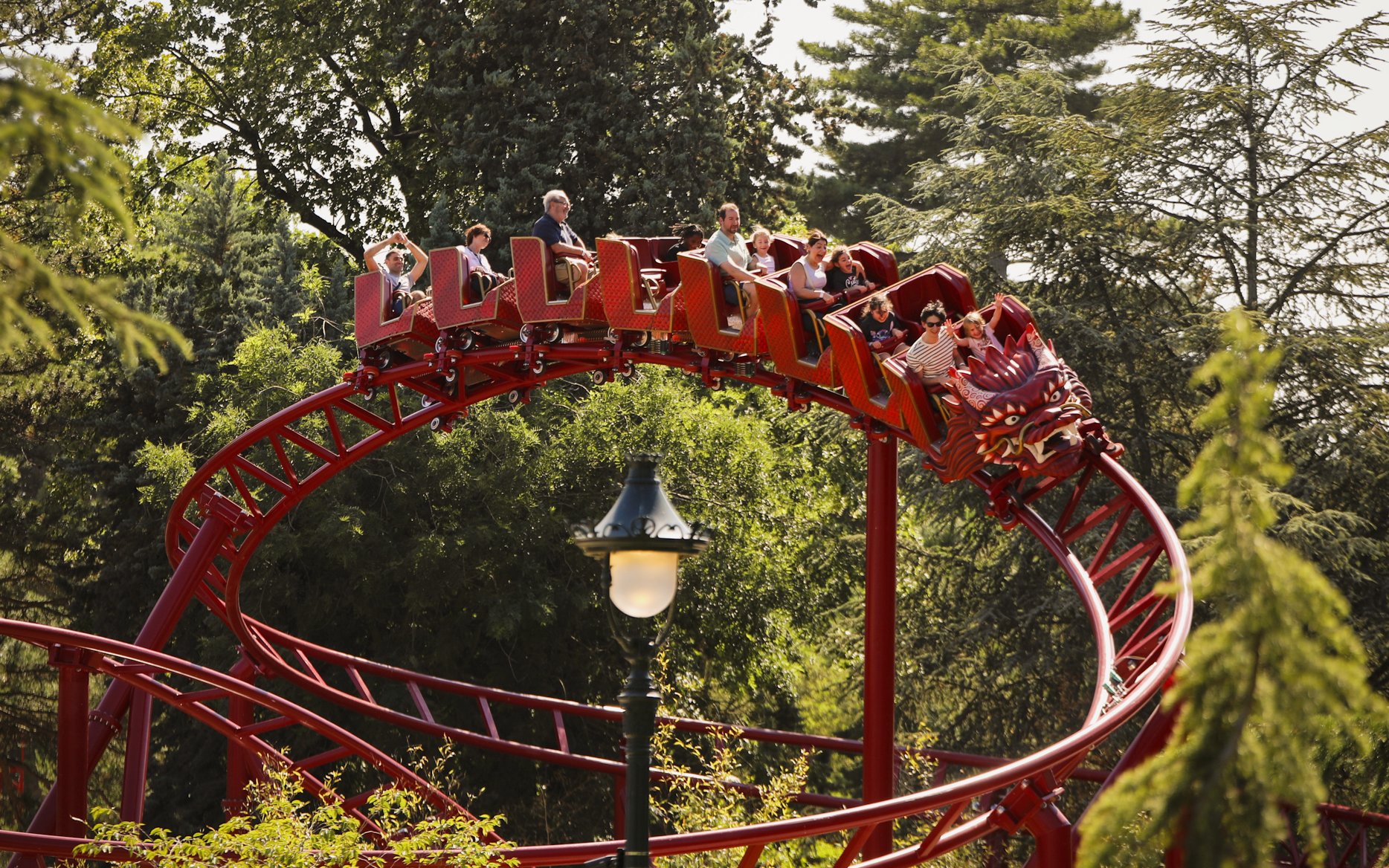 Roller coaster at Le Jardin d'Acclimatation with riders enjoying the ride.