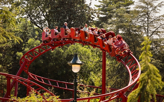 Roller coaster at Le Jardin d'Acclimatation with riders enjoying the ride.