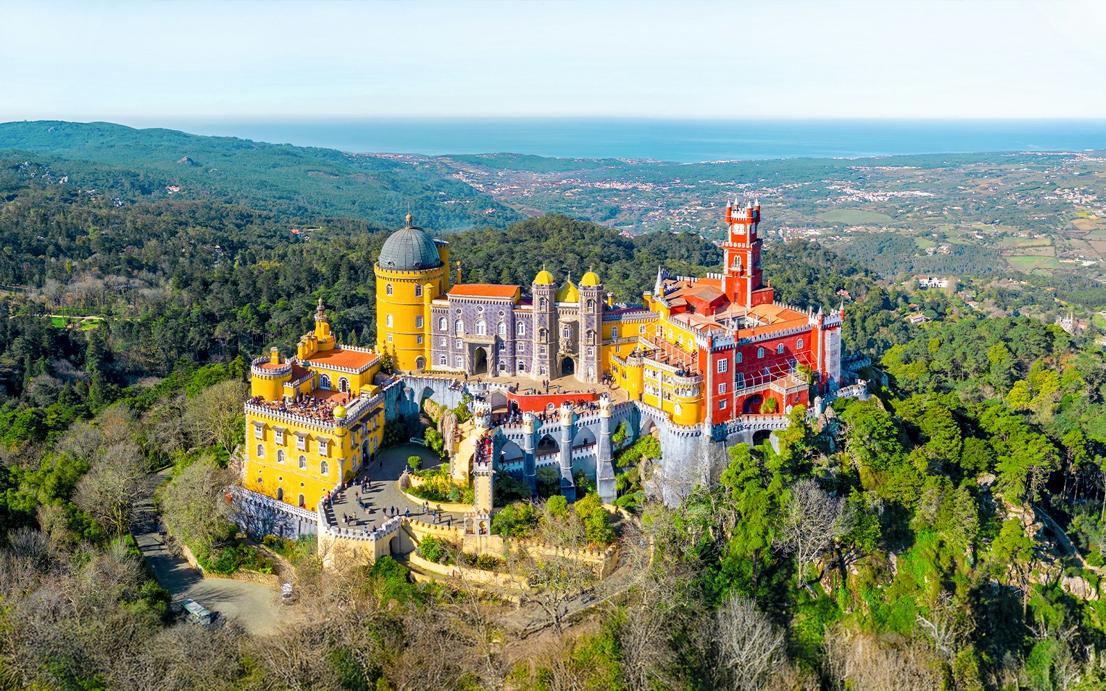 Aerial view of Pena Palace in Sintra, Portugal, surrounded by lush forest.