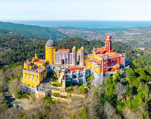 Pena Palace aerial view in Sintra, Portugal, showcasing vibrant architecture and lush surrounding forest.