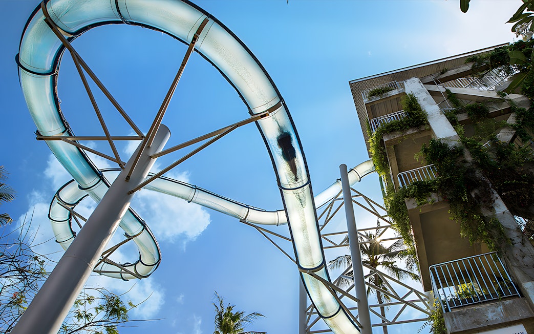 Water slide at Waterbom Bali with lush greenery and clear sky.