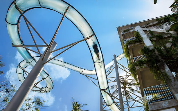 Water slide at Waterbom Bali with lush greenery and clear sky.