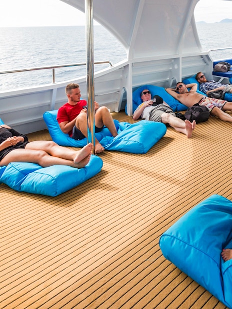 Tourists relaxing on bean bags on deck during Great Barrier Reef cruise from Cairns.