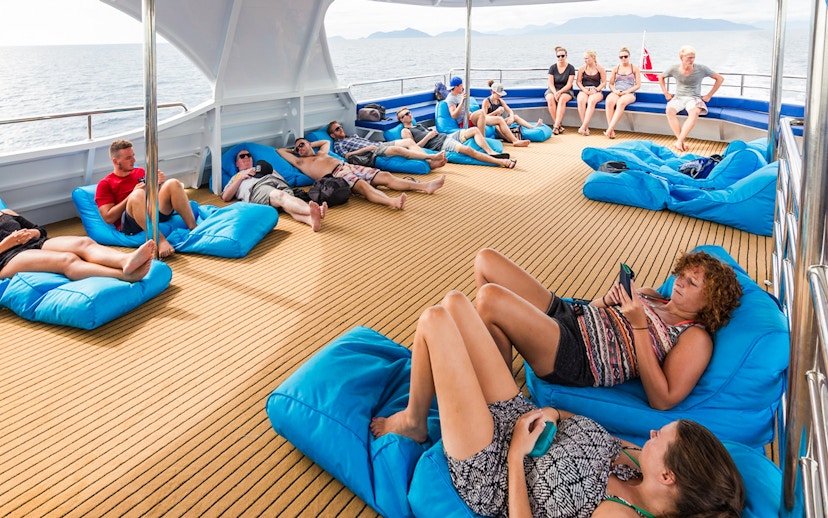 Tourists relaxing on bean bags on deck during Great Barrier Reef cruise from Cairns.