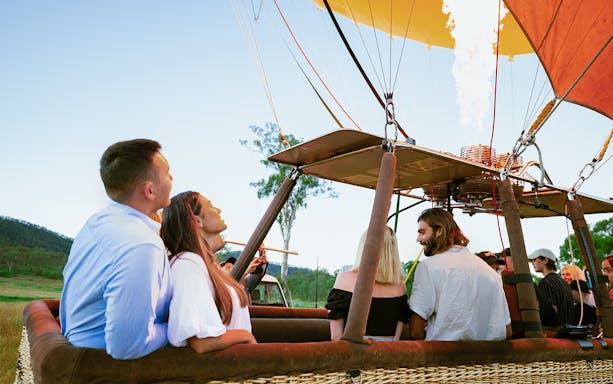 Couple enjoying a hot air balloon ride with scenic views, part of a luxury experience with hotel transfers.