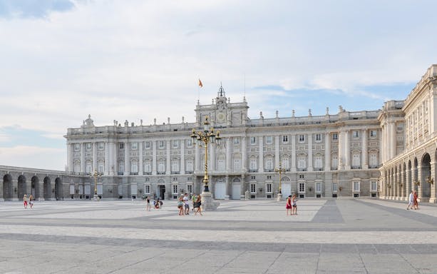 Royal Palace of Madrid facade with visitors in the courtyard.