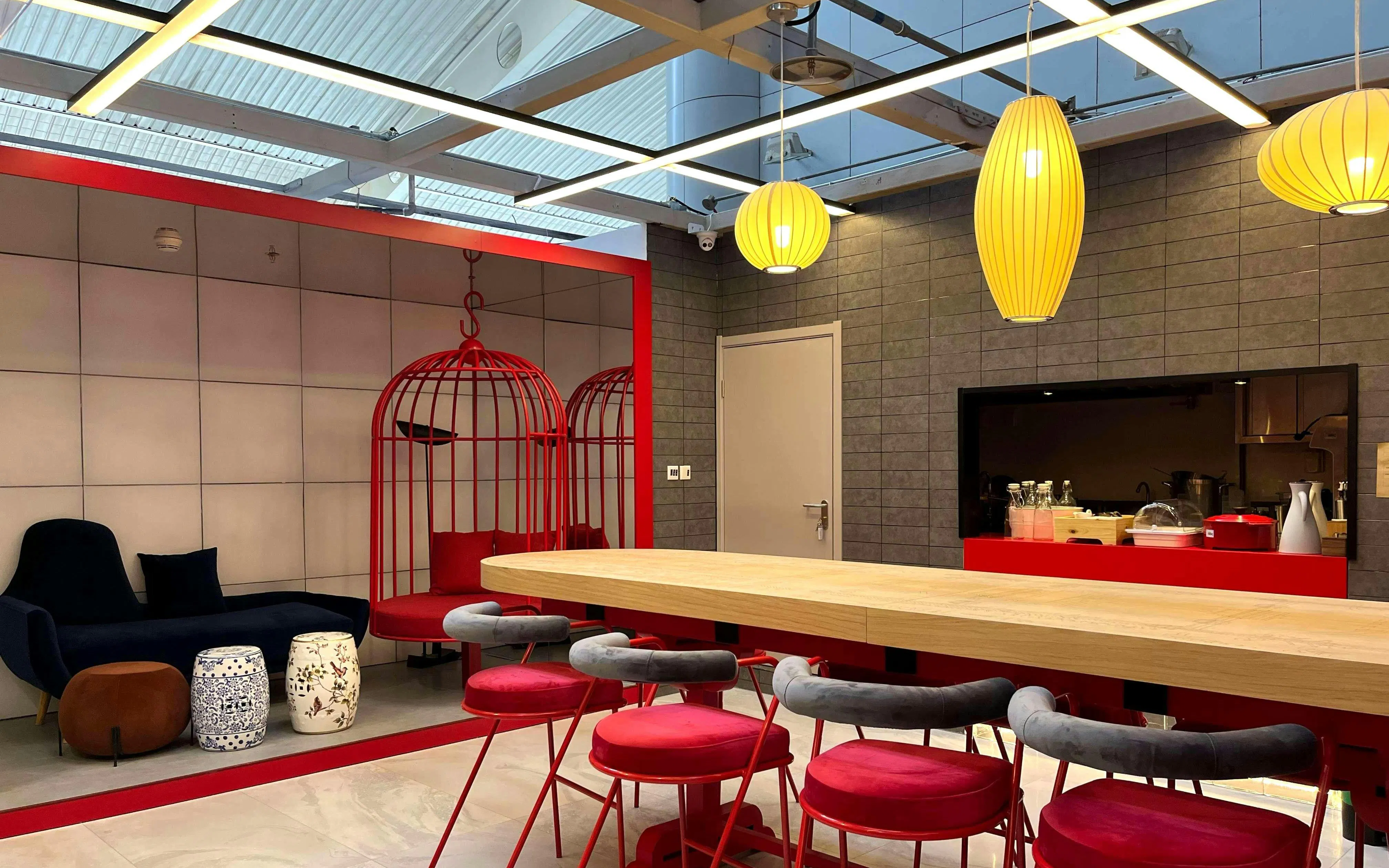 Seating area with red chairs and hanging lights at Barcelo Lounge, Beijing Capital International Airport.