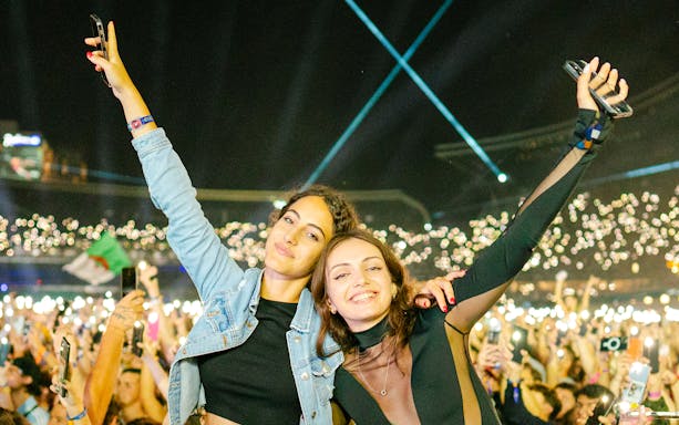 Crowd enjoying UNTOLD Music Festival Dubai with lights and raised hands.
