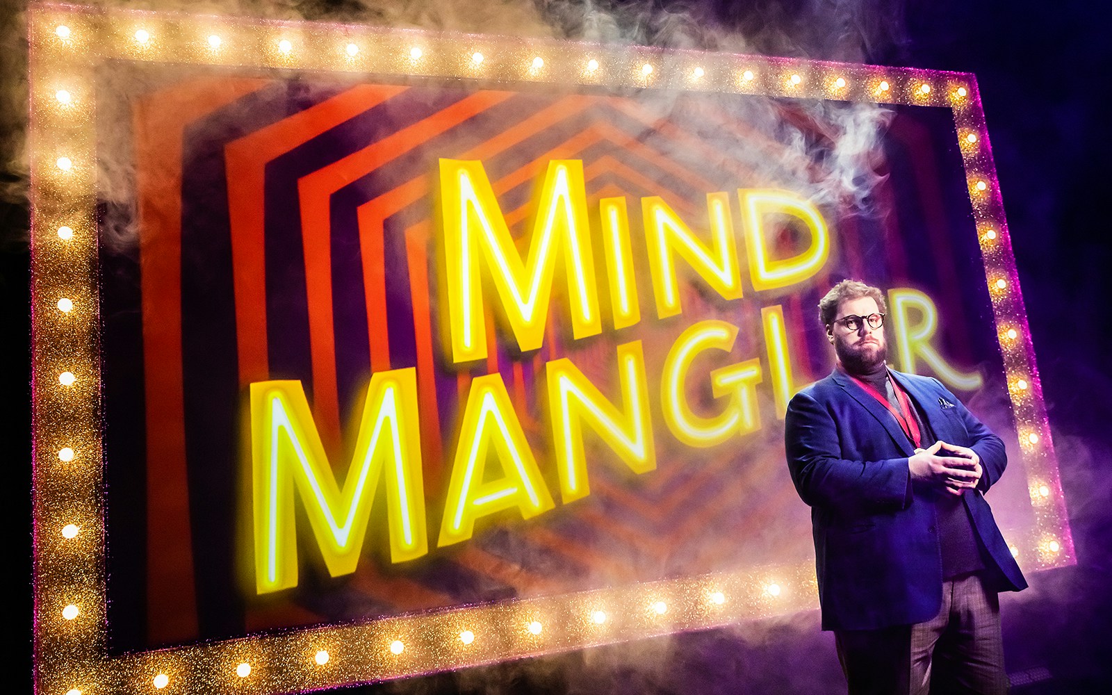 Performer on stage with "Mind Mangler" sign, part of the Tragic Circle show.