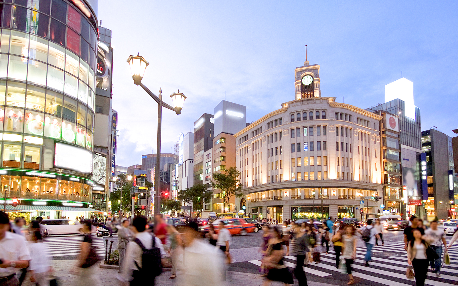Busy intersection in Ginza, Tokyo with iconic Wako building and bustling pedestrians.