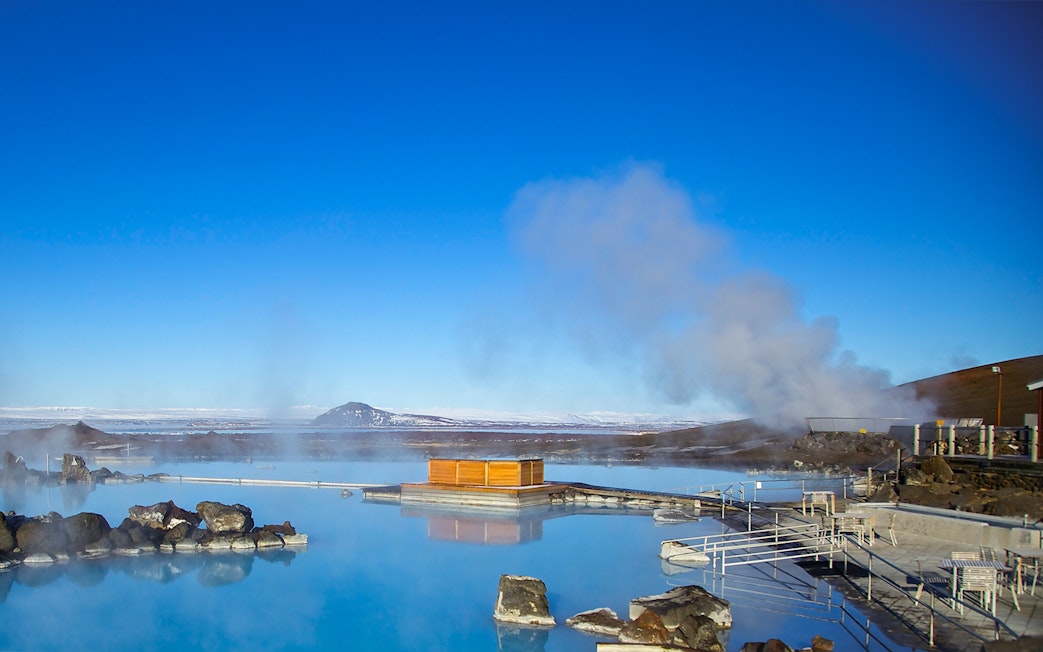 Myvatn Nature Baths with steaming geothermal pools and distant snowy mountains in Iceland.