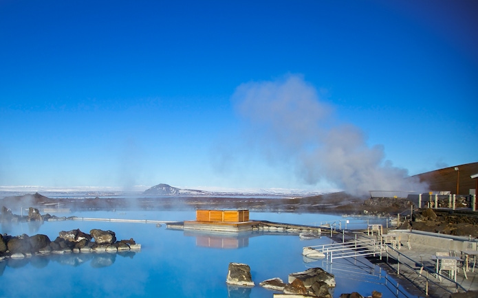 Myvatn Nature Baths with steaming geothermal pools and distant snowy mountains in Iceland.