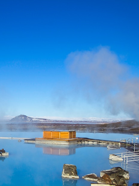 Myvatn Nature Baths with steaming geothermal pools and distant snowy mountains in Iceland.