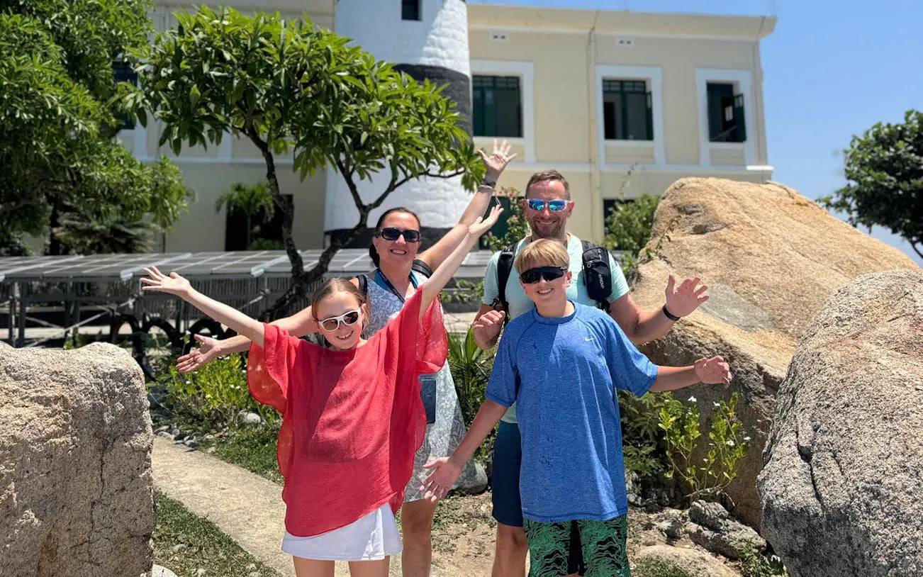 Family enjoying Nha Trang's Green Oasis Beach with lighthouse in background.