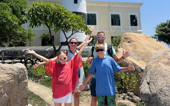Family enjoying Nha Trang's Green Oasis Beach with lighthouse in background.