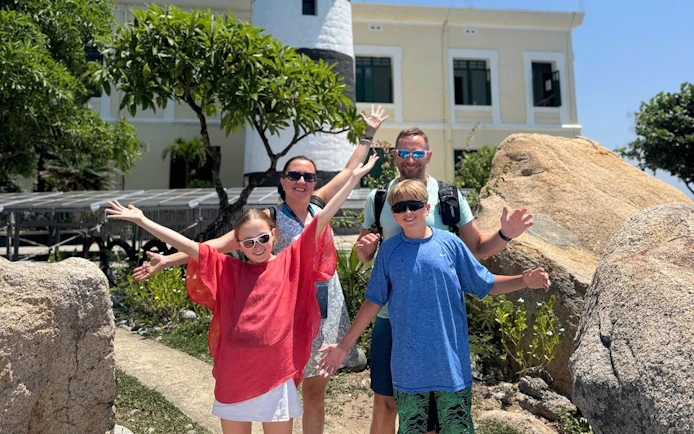 Family enjoying Nha Trang's Green Oasis Beach with lighthouse in background.
