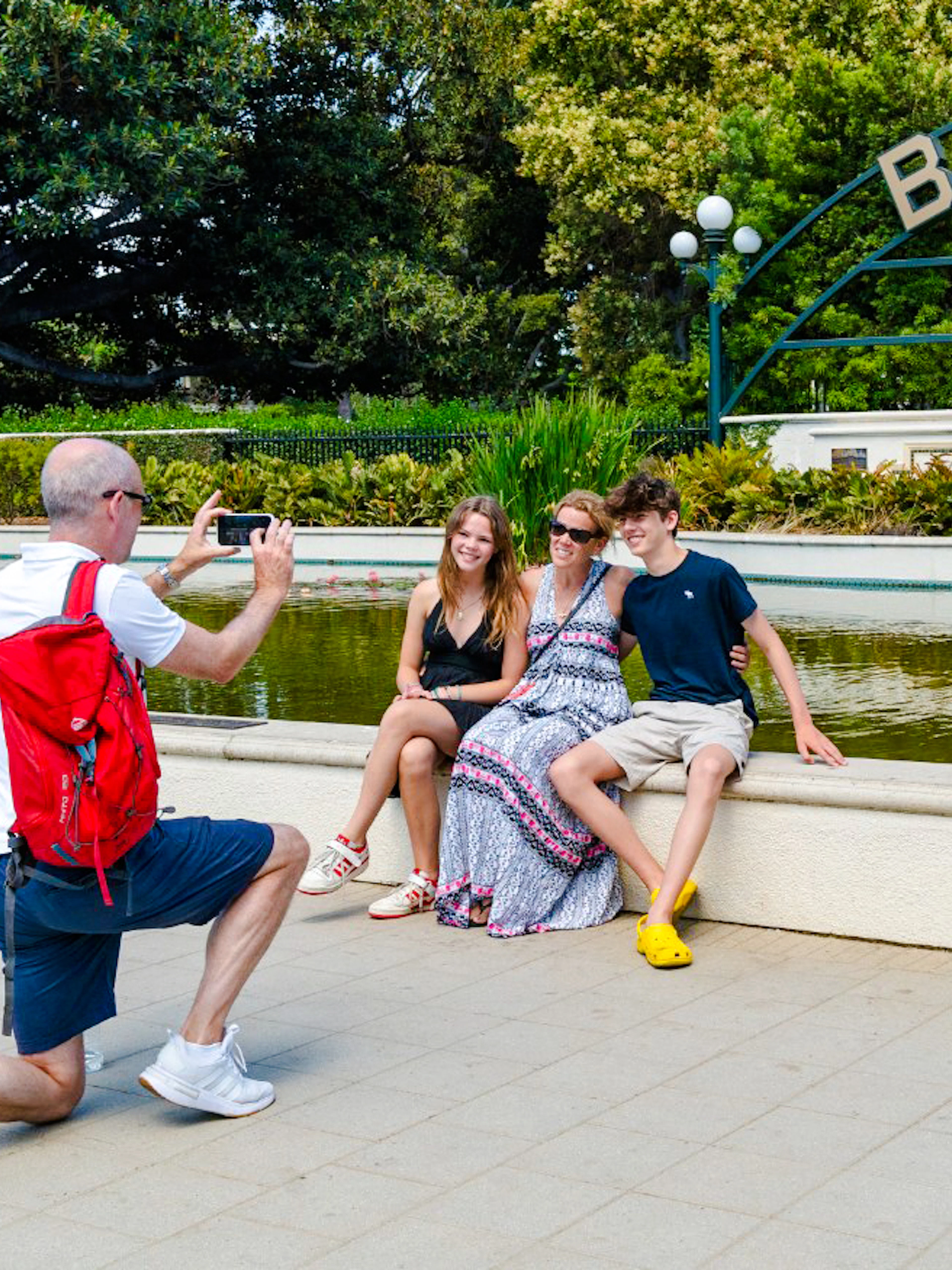 Man photographing family at Beverly Hills Sign, Beverly Gardens Park, California.