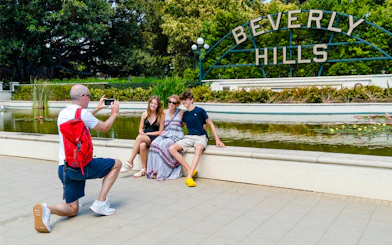 Man photographing family at Beverly Hills Sign, Beverly Gardens Park, California.