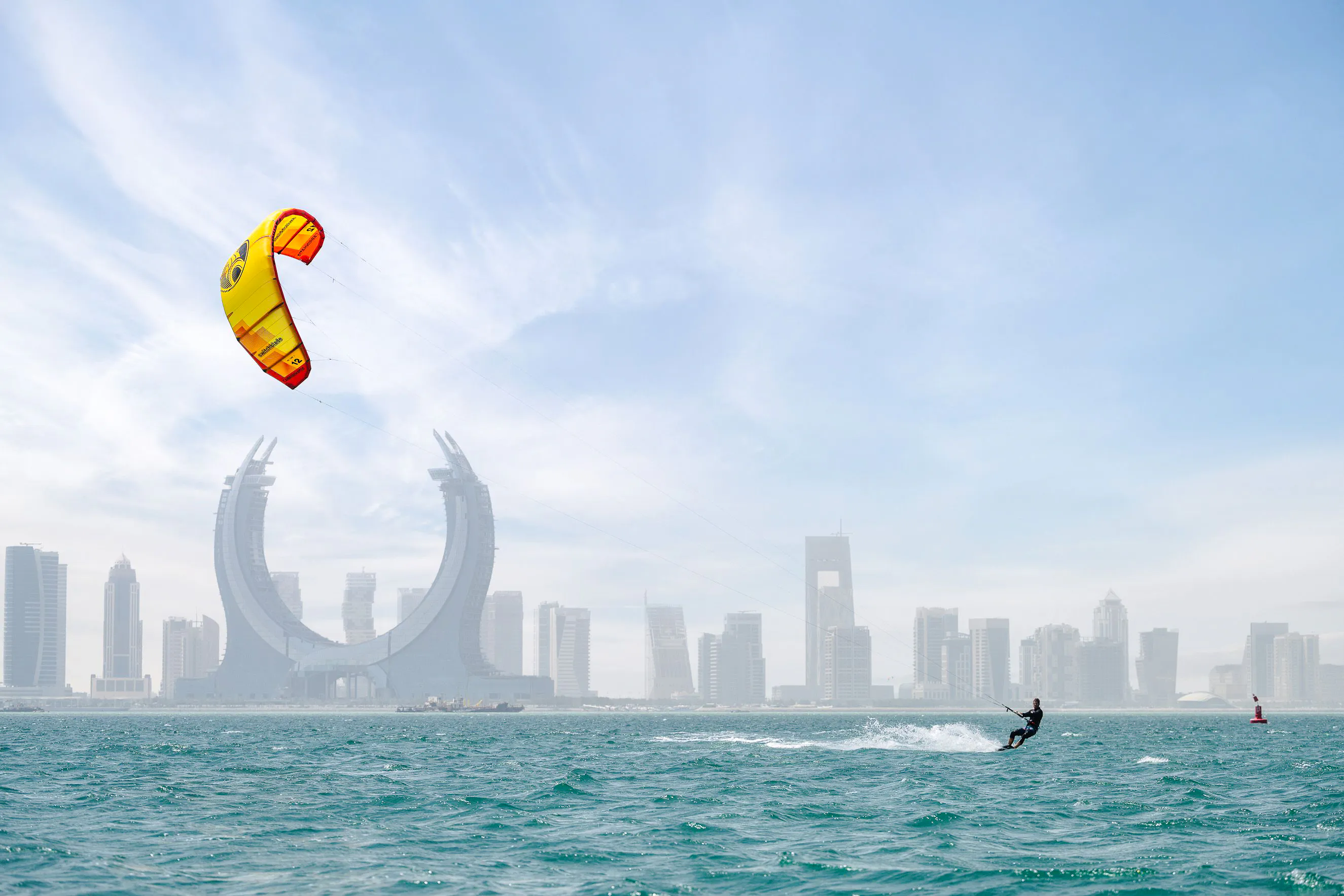 Kitesurfer on the water with Doha skyline in the background during a city tour and desert safari.