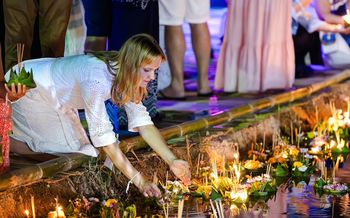 Woman placing a krathong into the water during Loy Krathong Festival 2025 in Chiang Mai.