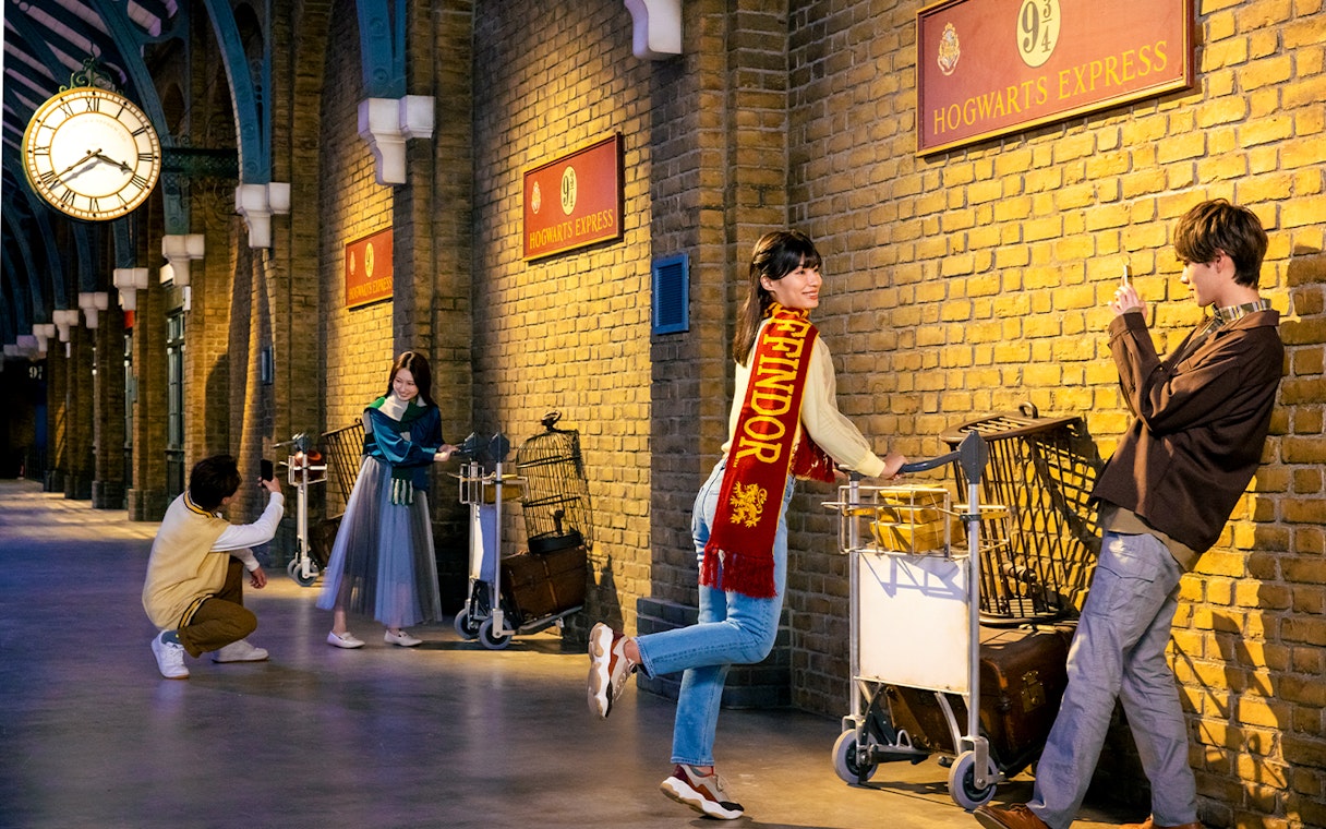 Visitors posing with luggage carts at Platform 9 3/4, Warner Bros. Studio Tour Tokyo.