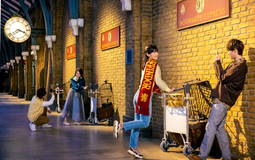 Visitors posing with luggage carts at Platform 9 3/4, Warner Bros. Studio Tour Tokyo.