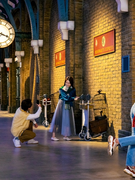 Visitors posing with luggage carts at Platform 9 3/4, Warner Bros. Studio Tour Tokyo.