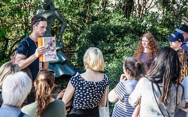 Tour guide explaining Montjuïc history to a group near a statue.
