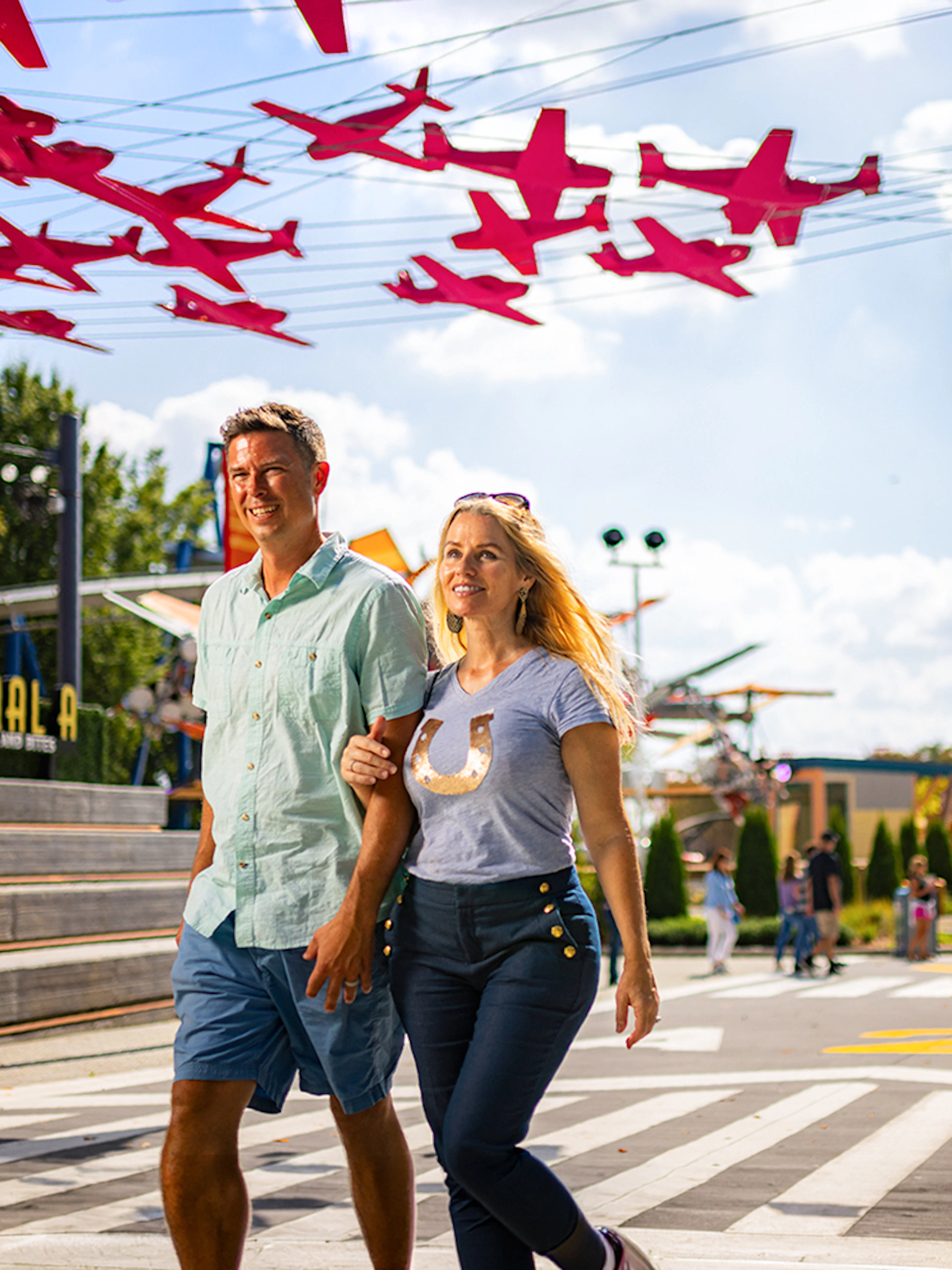 Visitors walking under red airplane decorations at Aeronautica Landing, Six Flags Carowinds.