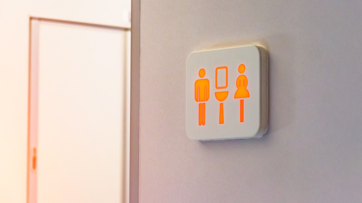 Restroom sign with male, female, and toilet symbols illuminated.