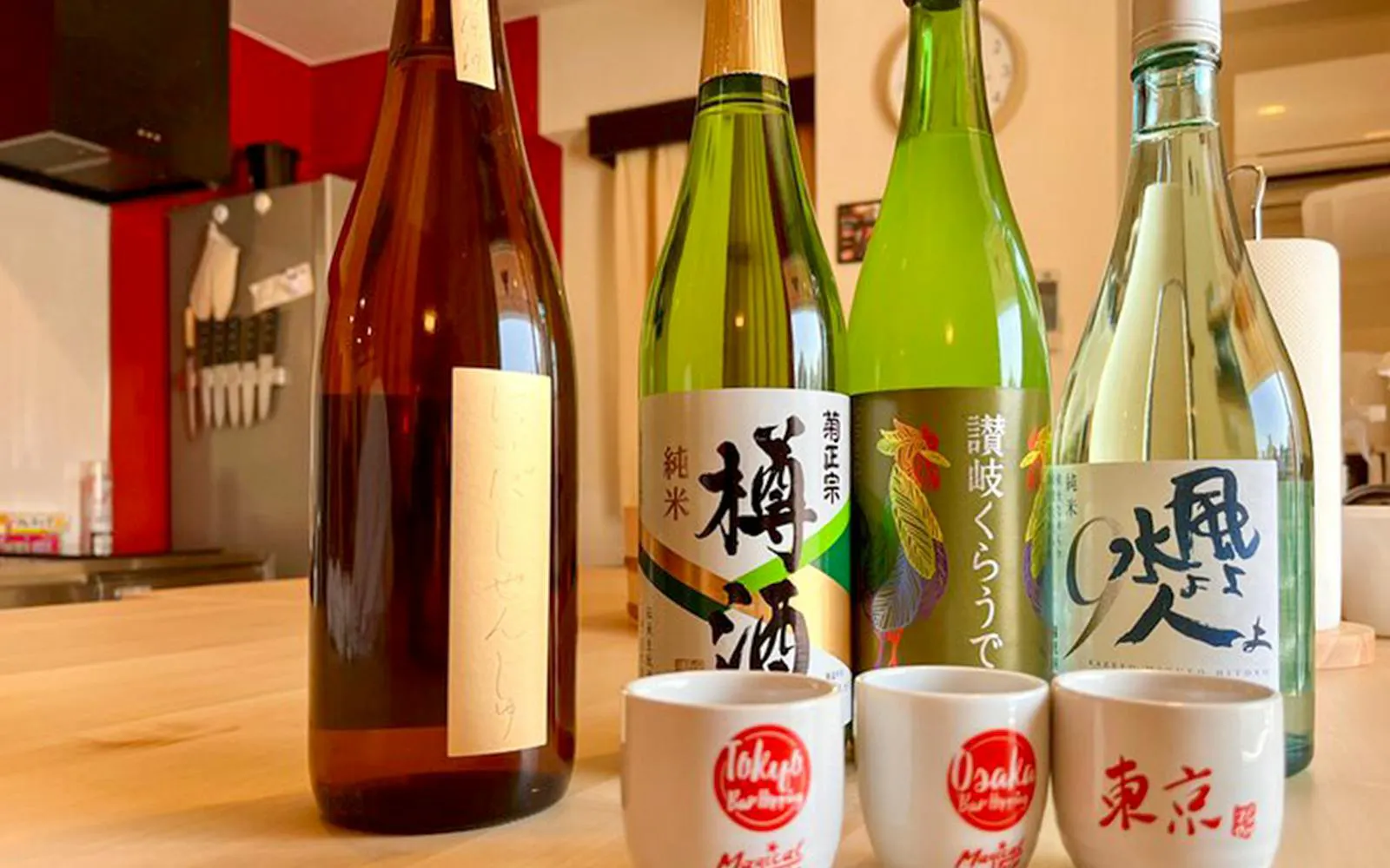 Bottles of sake and cups on a table in a Tokyo izakaya-style cooking class setting.