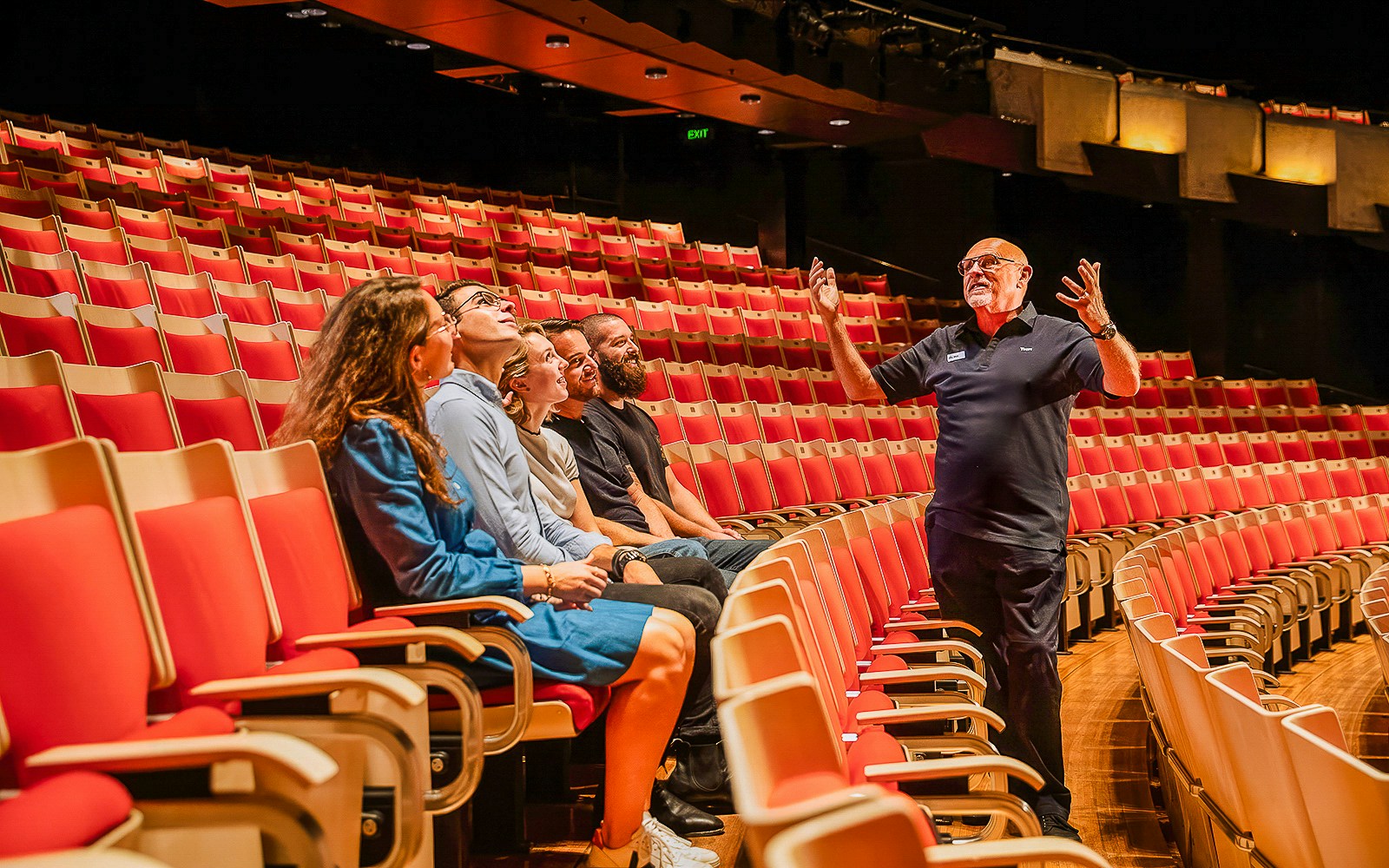 Tour guide explaining to visitors inside Joan Sutherland Theatre at Sydney Opera House.