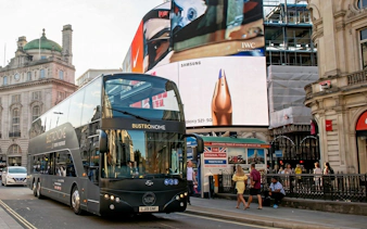Bustronome tour bus in London's Piccadilly Circus with digital billboards.
