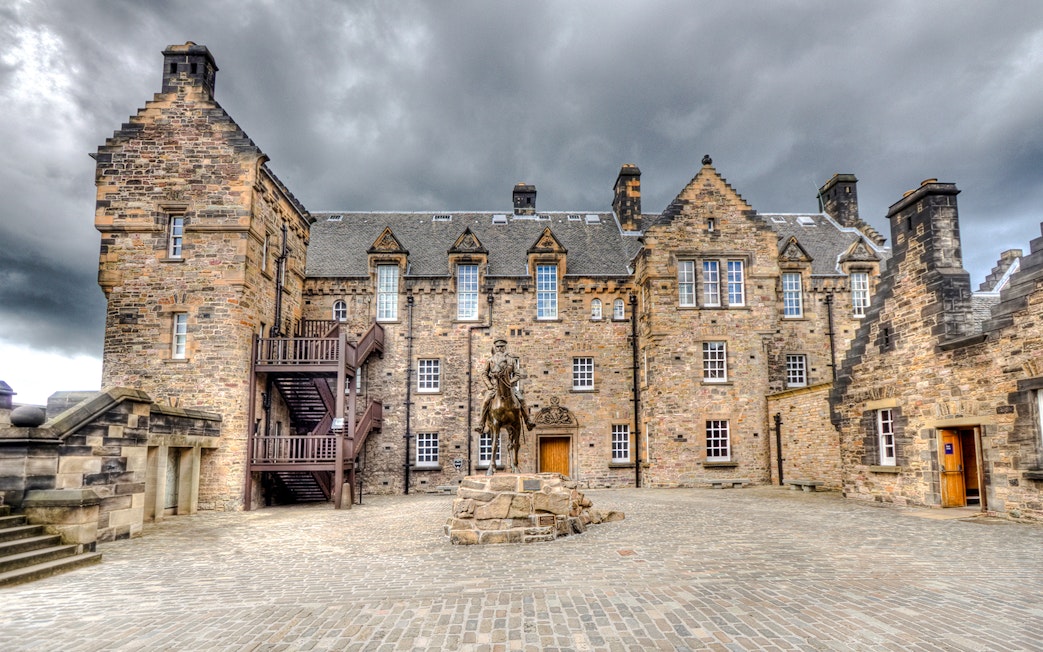 Edinburgh Castle Esplanade with historic stone buildings and equestrian statue.