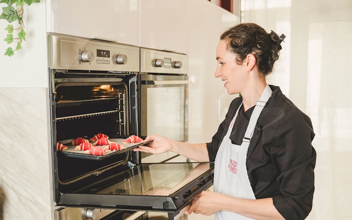 Baker placing croissants in oven during Paris croissant-making workshop.