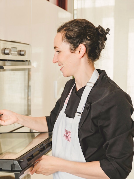 Baker placing croissants in oven during Paris croissant-making workshop.