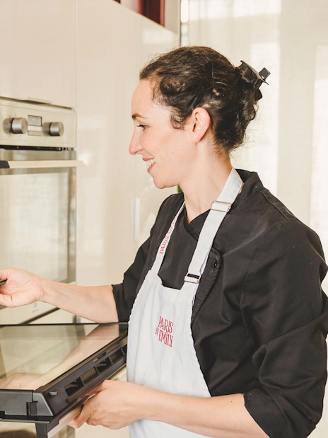 Baker placing croissants in oven during Paris croissant-making workshop.